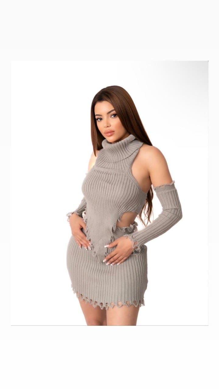 Daniela stands against a white studio background in a grey ribbed mini dress with cut-out shoulders, hands on hips.